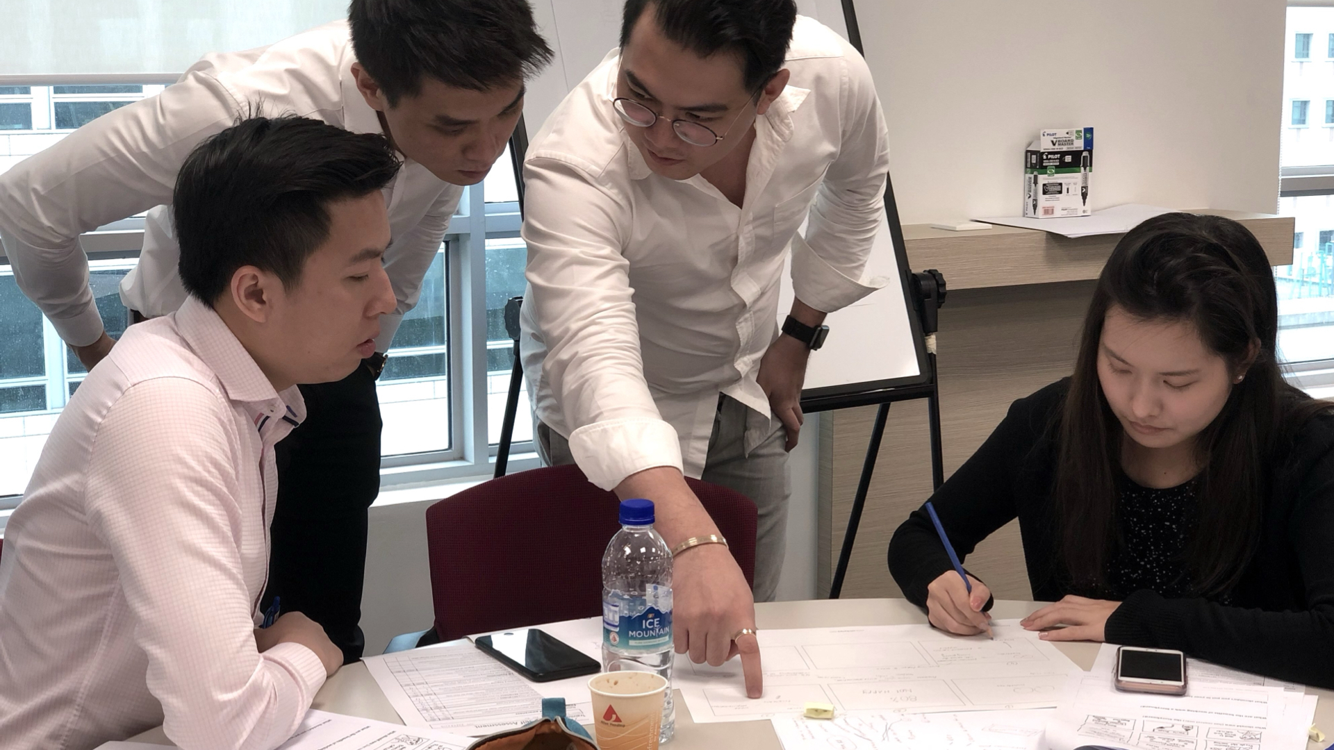 A team discussing a presentation storyboard while one person points to its sequence and another records changes